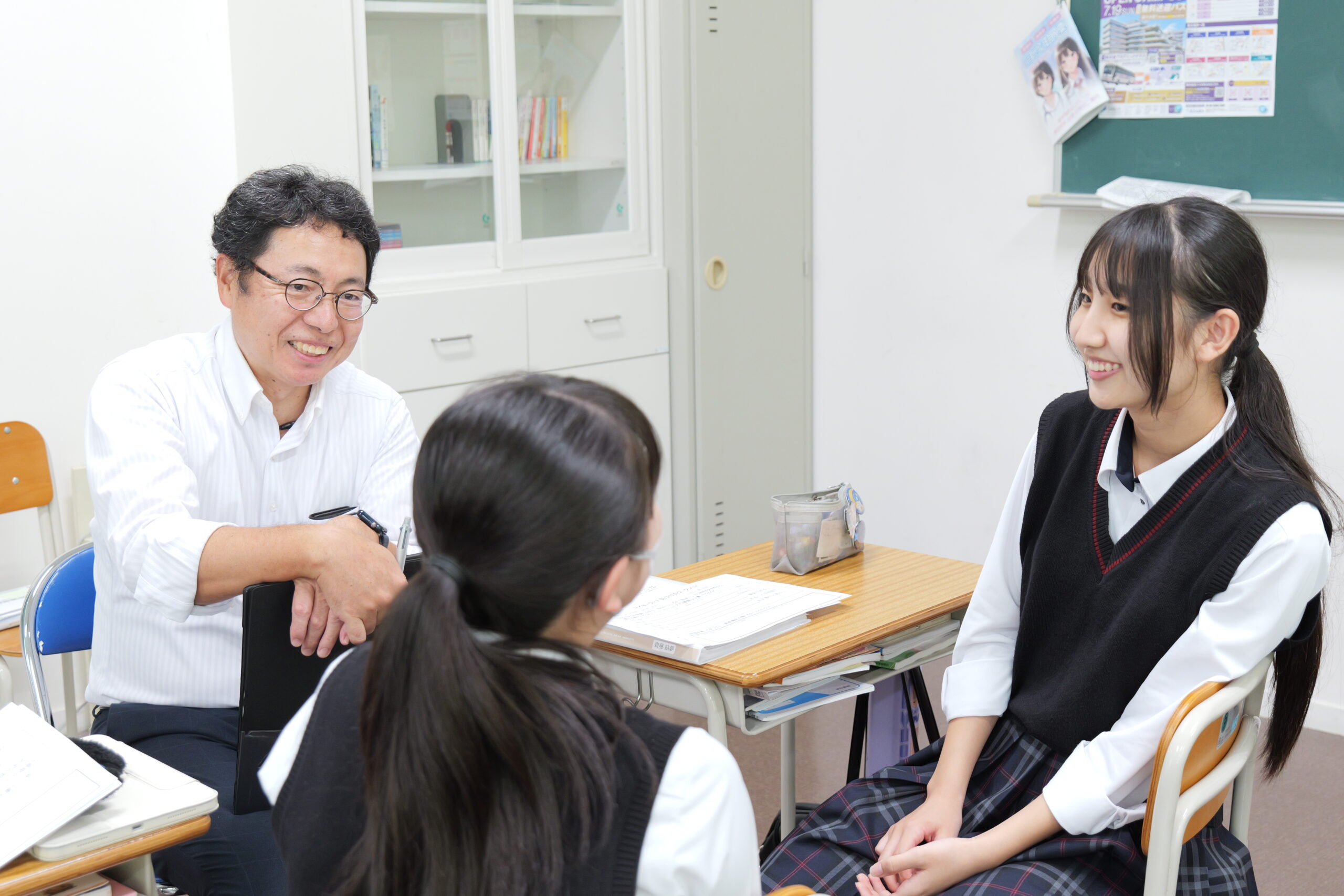 教室で笑顔で対話する生徒と大人
