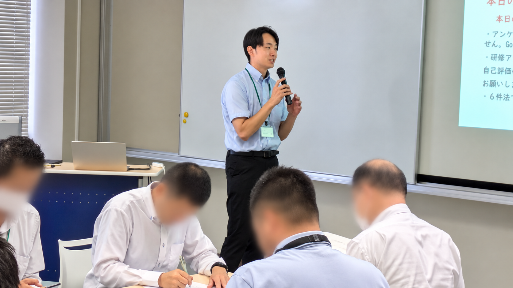 マイクを持って話す講師と教員研修の参加者